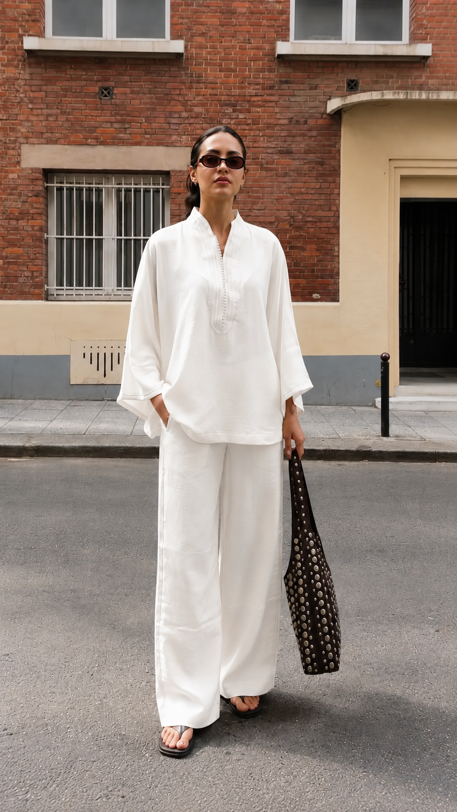 Model wearing a white embroidered split-neck tunic with matching wide-leg pants