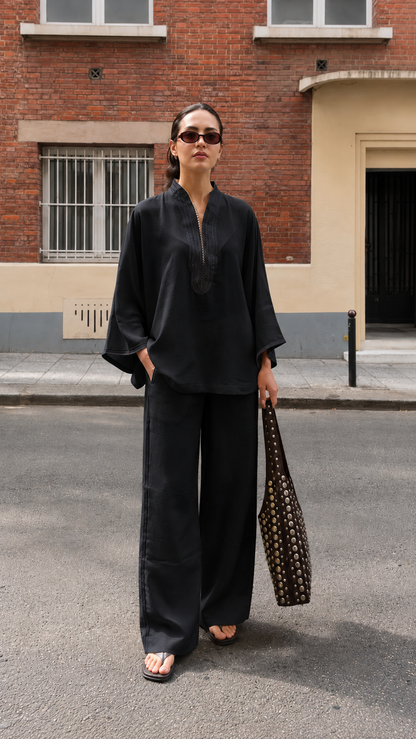 Model wearing a black relaxed two-piece tunic and wide-leg pants outfit