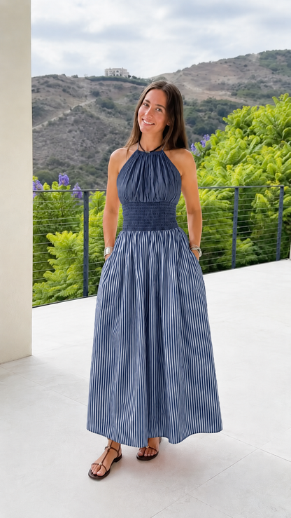 Front view of a navy striped halter maxi dress with a flowing maxi silhouette